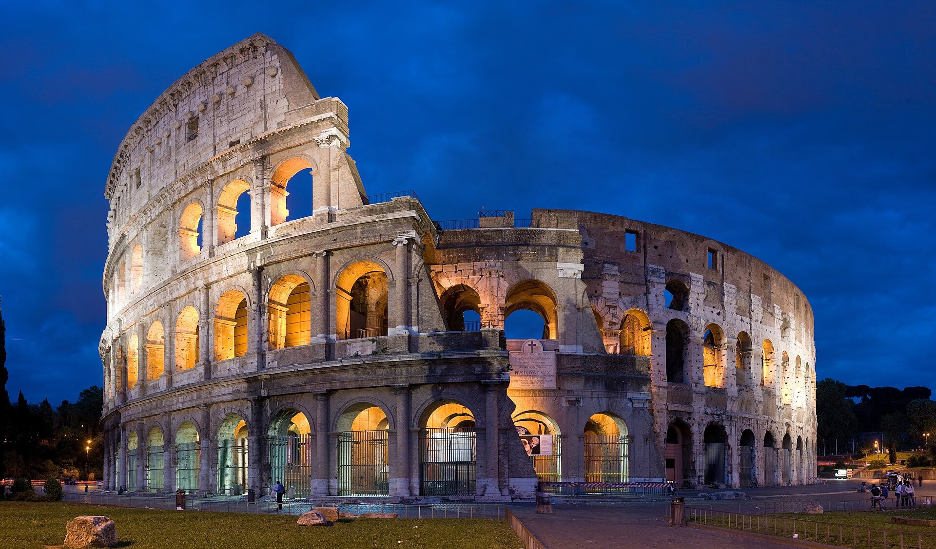 Rome's Colosseum illuminated against a deep blue evening sky